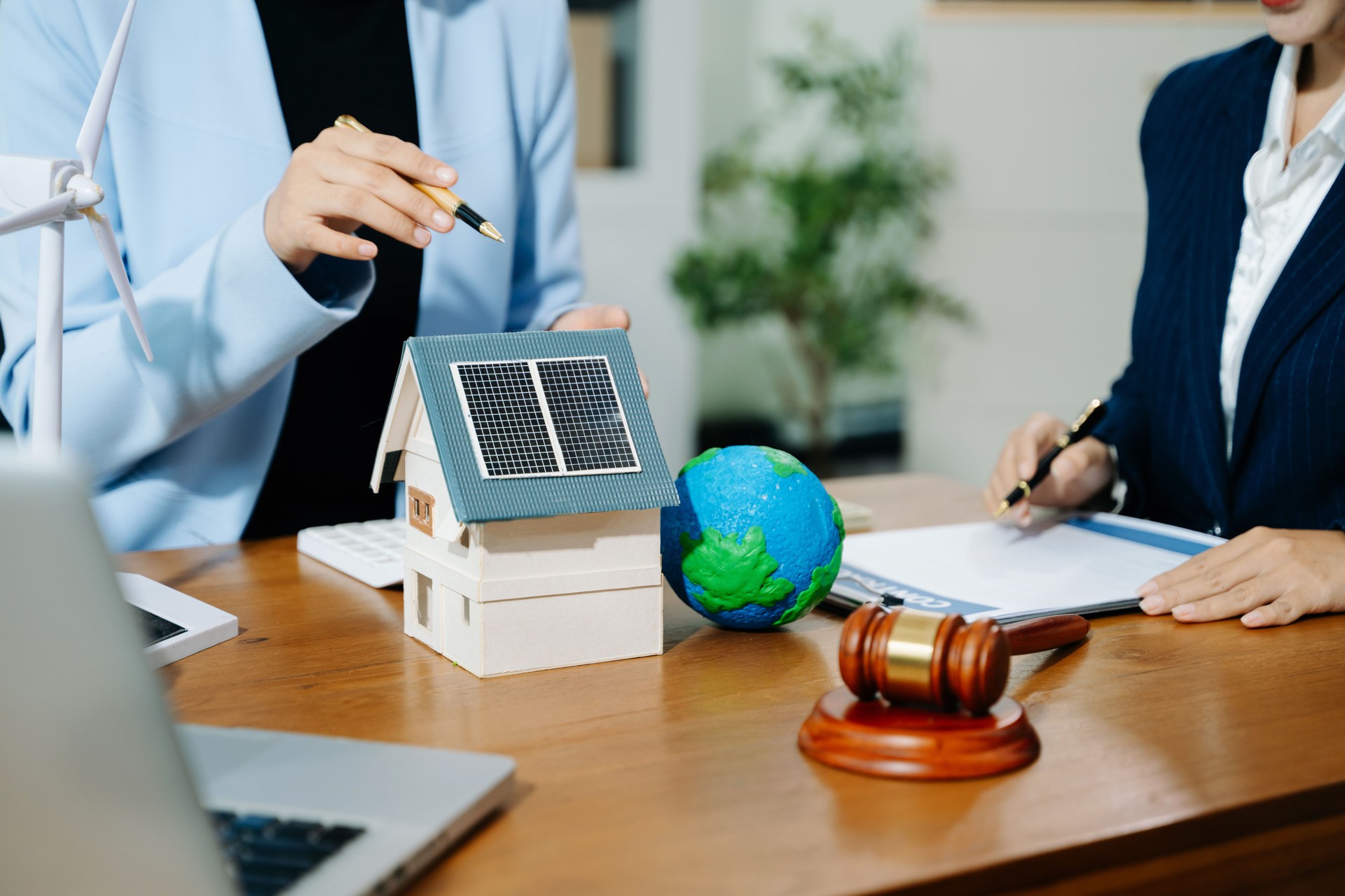 Two professionals plan global sustainability with eco housing, legal contracts, solar energy, and financial investment